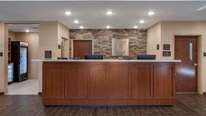 A reception area with a wooden reception desk, a stone accent wall, and a door with a sign.