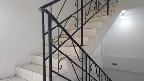 A staircase with a black metal railing and white tiled steps. - Ancol Homestay (Jakarta)