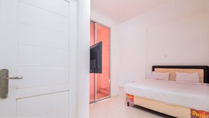 A bedroom with a bed, a television mounted on the wall, and a sliding door leading to another room. - Ancol Homestay (Jakarta)