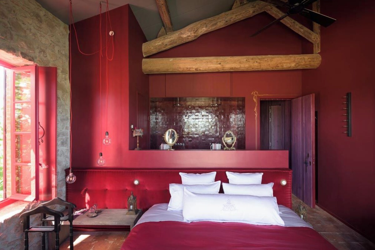 Un dormitorio con una cama grande, techo de madera y pared roja.