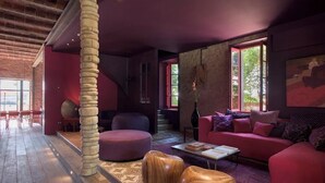 Un interior moderno con un gran pilar de madera, un sofá rojo y una alfombra estampada.