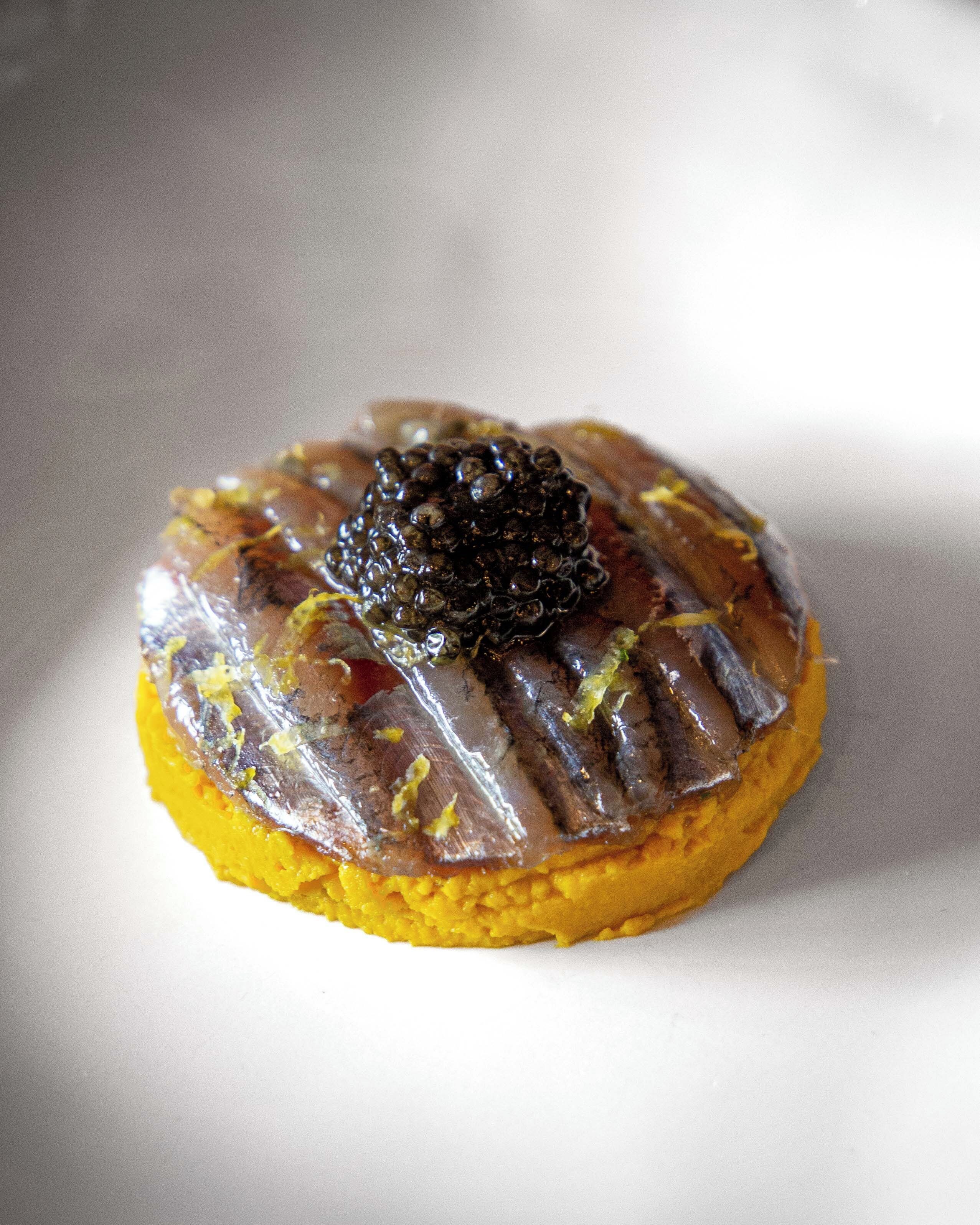 A dessert with a clear gelatin layer and a black caviar topping on a yellow base.