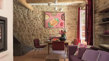 Un intérieur rustique en pierre, comprenant un coin repas, un canapé et une cheminée.