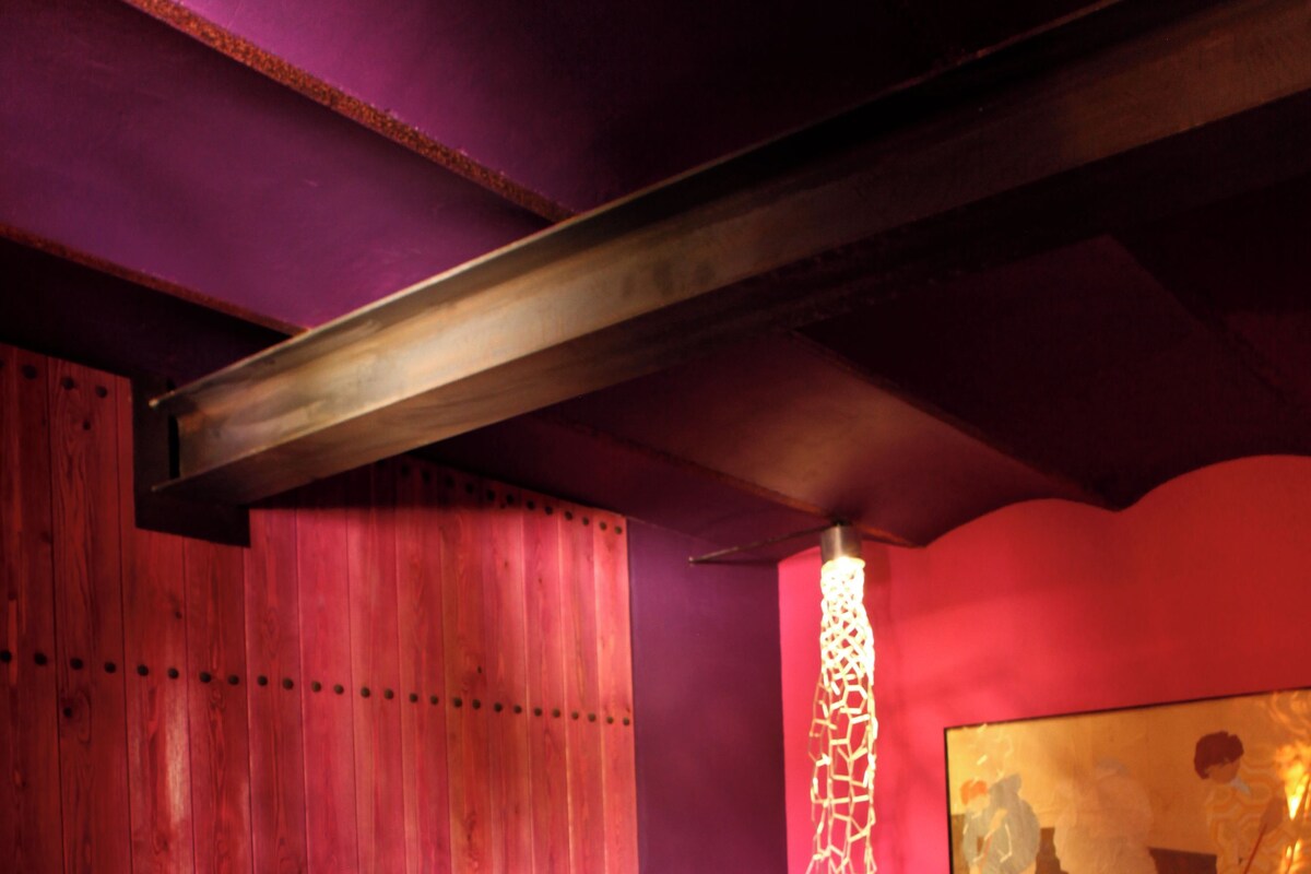 Un dormitorio con cama, cabecero de madera, un cuadro en la pared y una lámpara decorativa.