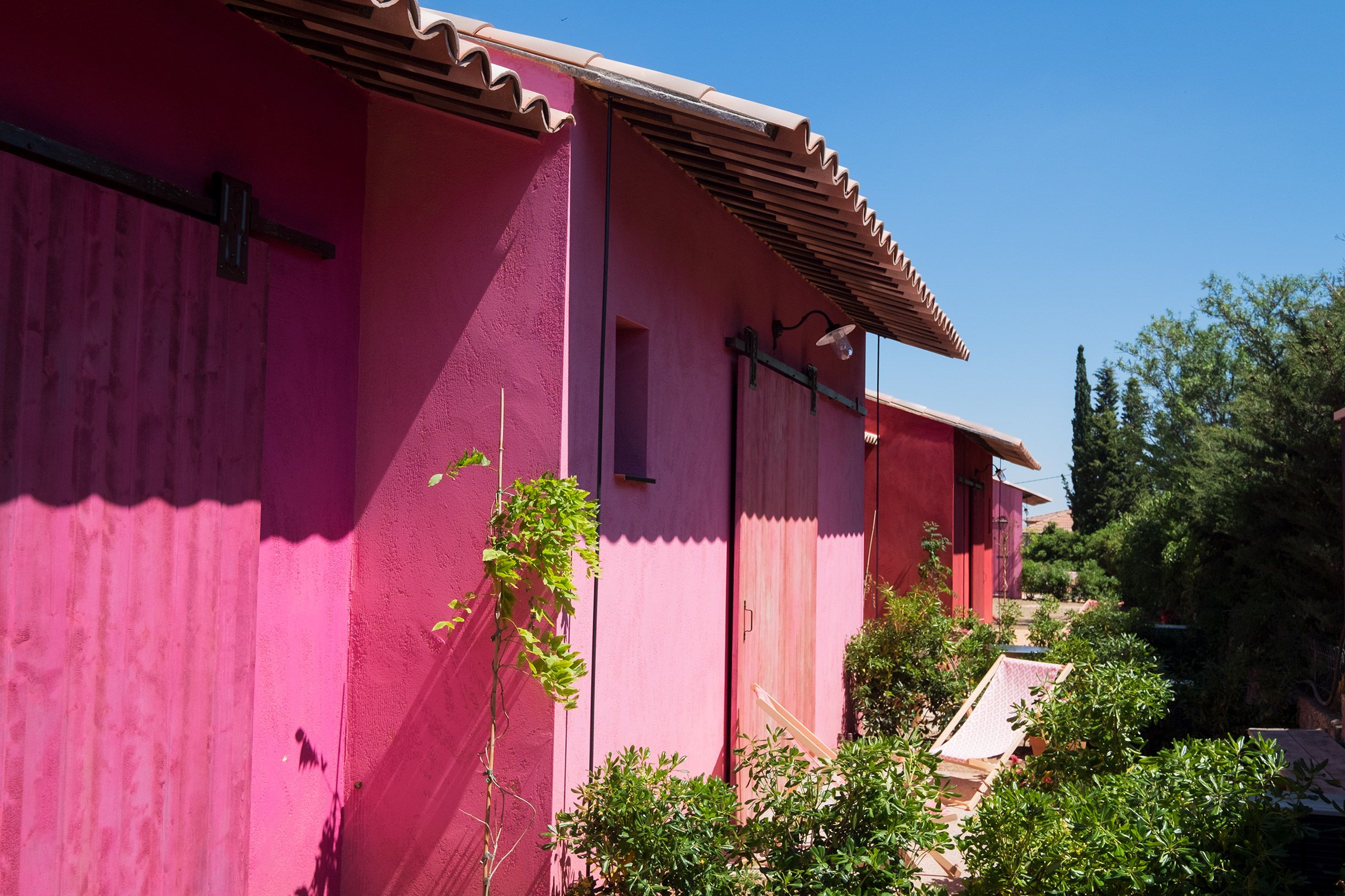 A row of pink buildings with a tiled roof and a small window.