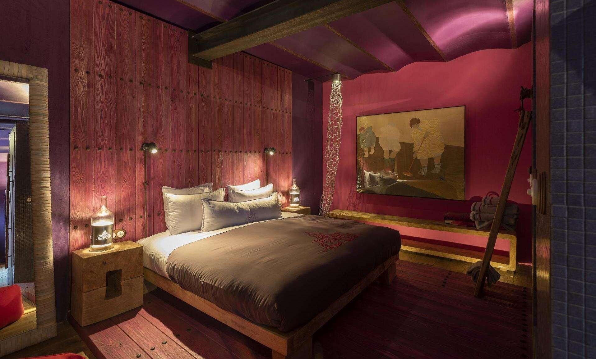 Un dormitorio con una cama de madera, dos mesitas de noche, un cuadro y una guitarra.