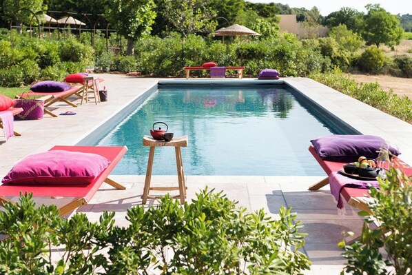 A swimming pool with lounge chairs and a small table with a teapot.