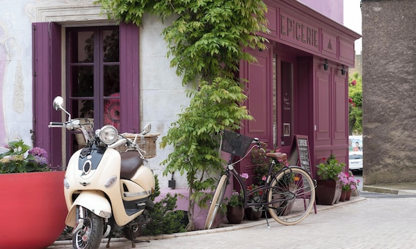 A vintage scooter parked in front of a building with purple shutters and a sign reading 'EPICERIE.'