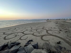 Ein Strand mit Sandmustern und Felsen im Vordergrund.