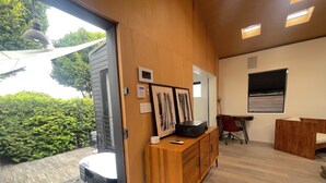 A modern interior with a wooden desk, a red chair, and a view of greenery outside.