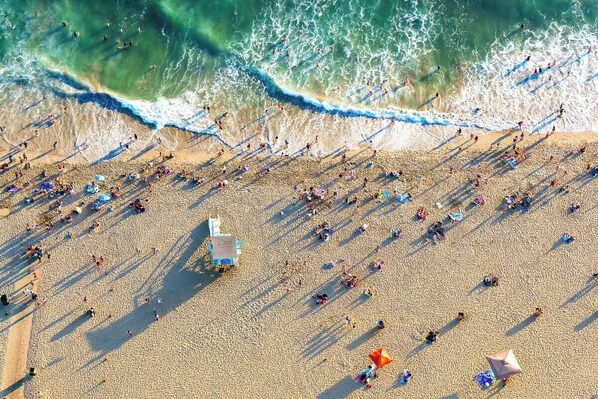 An aerial view of a beach with people, umbrellas, and a lifeguard stand. - Venice Beach Private Bungalow Walk to Abbot Kinney (Venice)