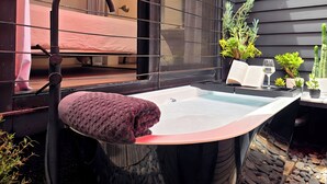 A bathroom with a bathtub, a towel, a mirror, and a window.