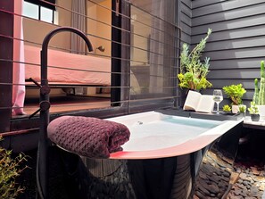 A bathroom with a bathtub, a towel, a mirror, and a window.