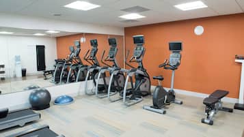 A gym with multiple treadmills, stationary bikes, and exercise balls.