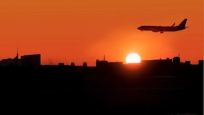 Un avion survolant les contours d’une ville au coucher du soleil.