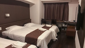 Une chambre d’hôtel avec deux lits, un bureau, une chaise et un téléviseur.