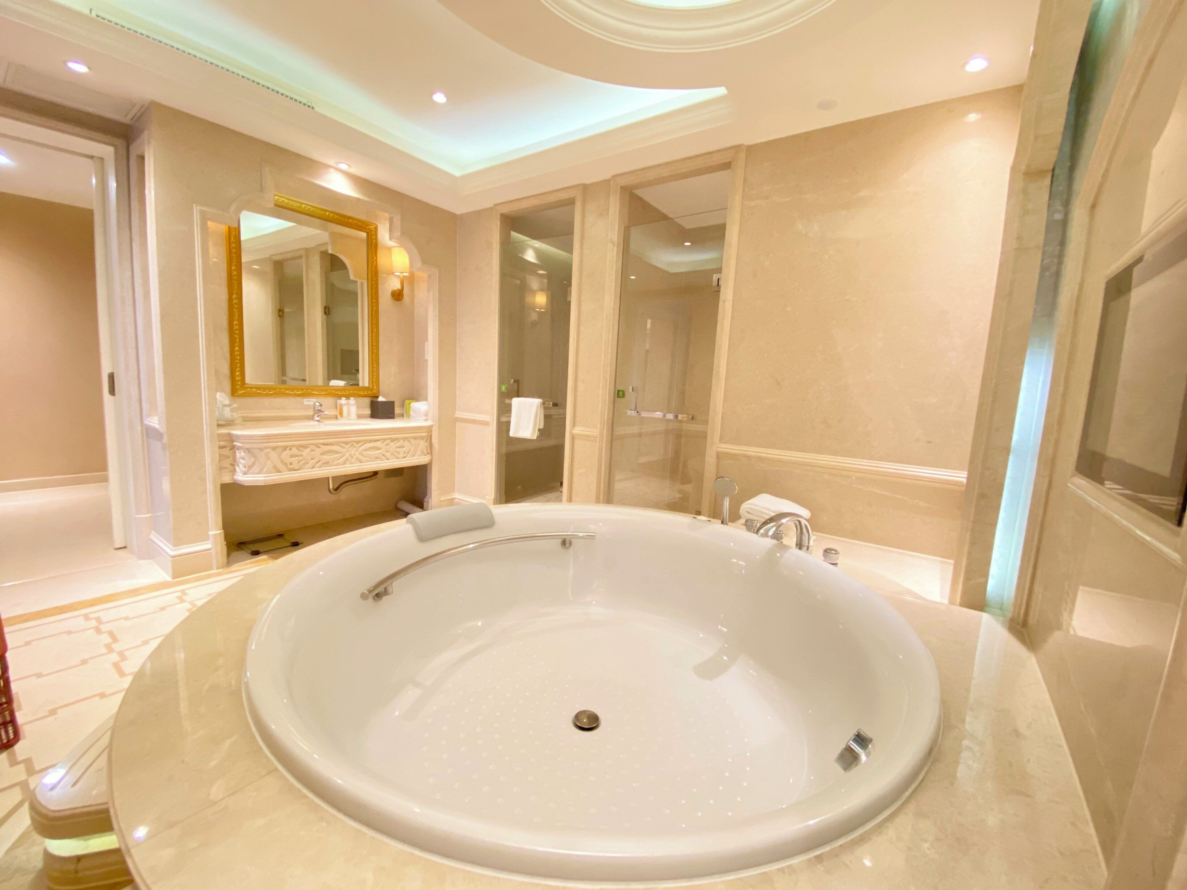 A large oval bathtub in a well-lit bathroom with a mirror and vanity.