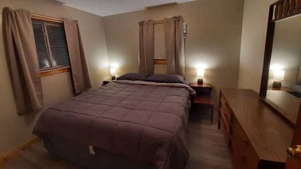 A bedroom with a bed, bedside tables, a dresser, and a mirror.