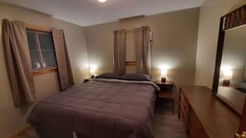 A bedroom with a bed, bedside tables, a dresser, and a mirror.