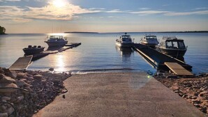 A calm lake with boats docked at a pier, surrounded by rocks and a clear sky.
