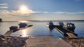 A calm lake with boats docked at a pier, surrounded by rocks and a clear sky.