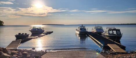 A calm lake with boats docked at a pier, surrounded by rocks and a clear sky.