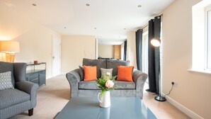 A modern living room with a grey sofa, a coffee table, and a vase of flowers. - Apartment 9 (Worksop)