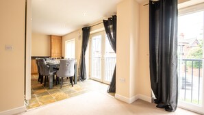 A spacious room with a dining area, a large window with curtains, and a view of the outside. - Apartment 9 (Worksop)