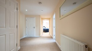 A hallway with white doors, a radiator, and a bed in the distance. - Apartment 9 (Worksop)
