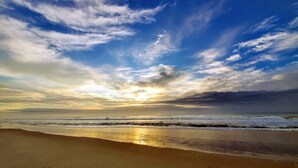 Une plage avec des vagues et un coucher de soleil.