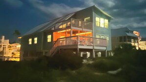 Uma casa de dois andares com varanda no andar superior, rodeada por outros edifícios.