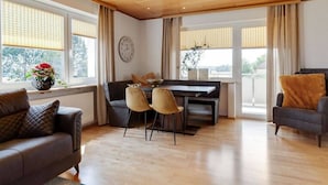 Een moderne woonkamer met een bank, eettafel, stoelen en een piano.