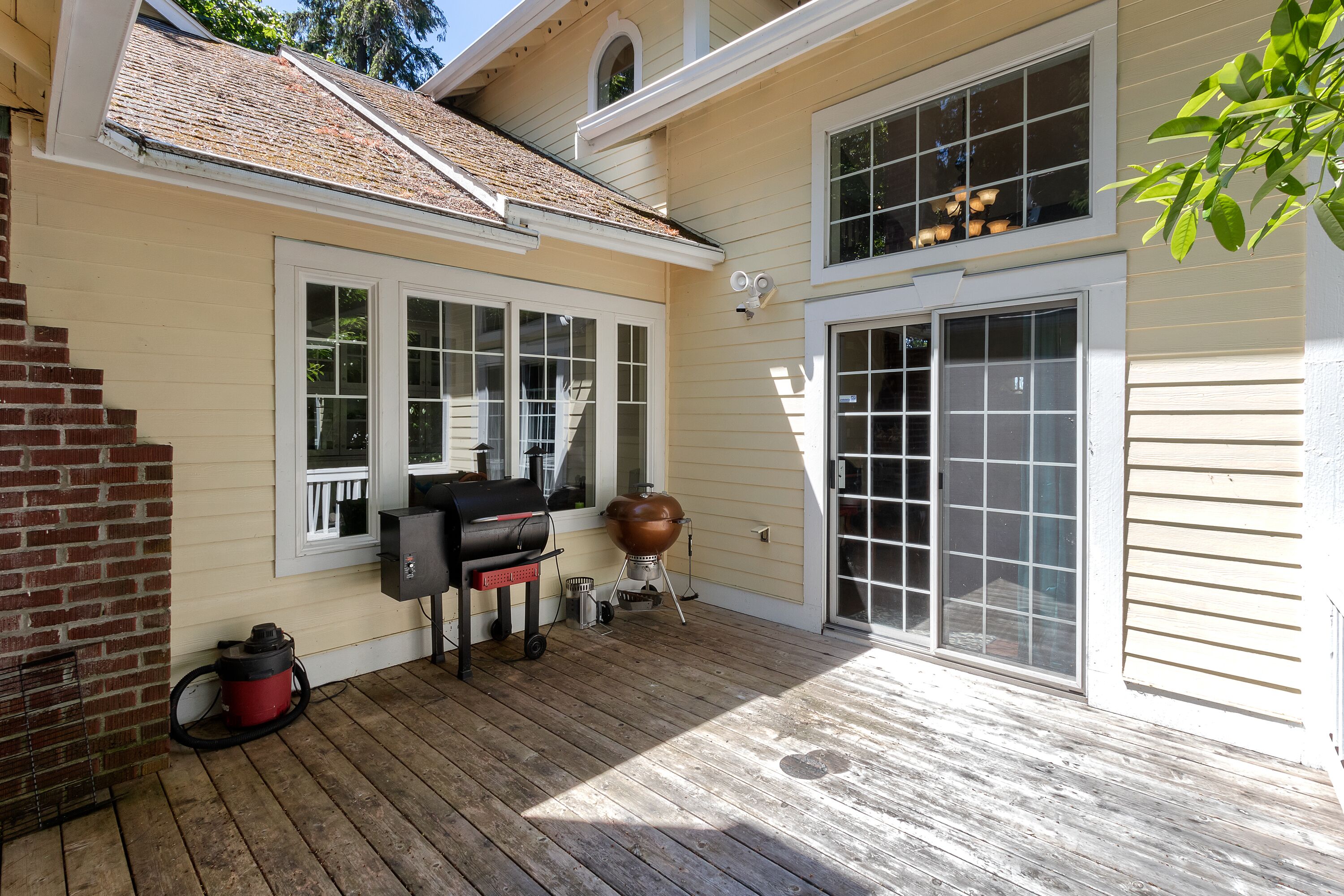 A covered patio with a grill, a large pot, and a water heater.