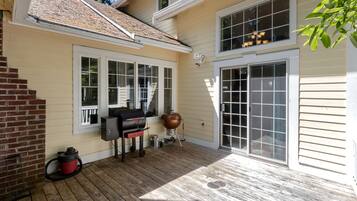 A covered patio with a grill, a large pot, and a water heater.