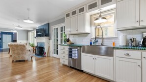 Una cocina amplia con armarios blancos, un lavamanos de acero inoxidable y un salpicadero de azulejos.