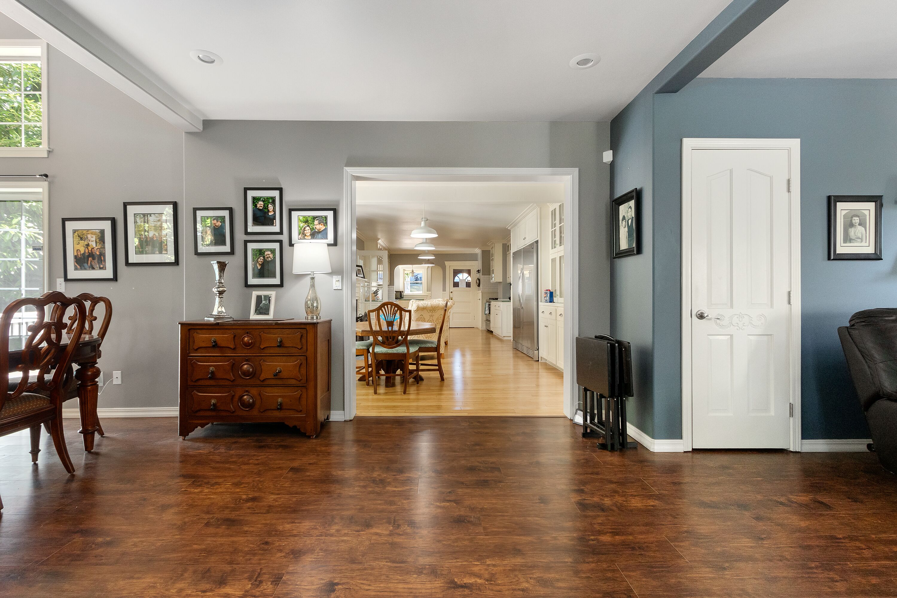 A spacious room with hardwood flooring, a dining area with a table and chairs, and a door leading to another room.