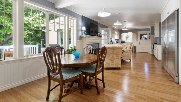 Una cocina amplia con armarios de madera, un refrigerador de acero inoxidable y un comedor con mesa y sillas de madera.
