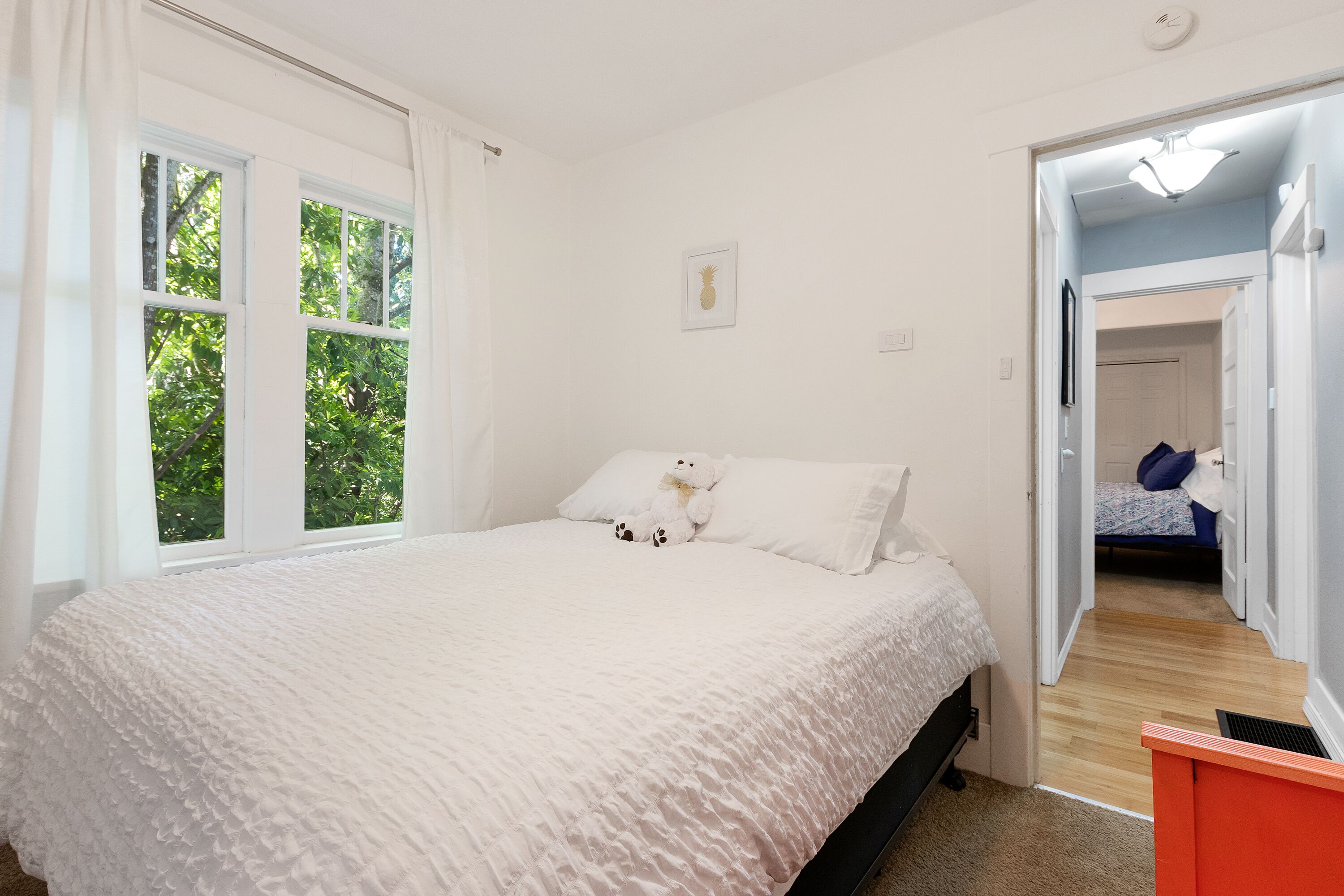 Ein Schlafzimmer mit einem Bett, einem Fenster und einer Tür zu einem anderen Raum.