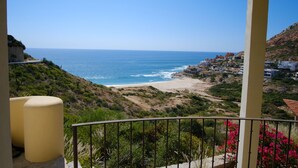 Een balkon met uitzicht op een strand en kustplaats.