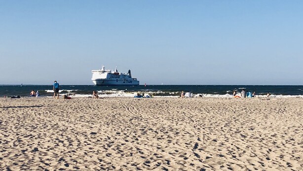 A beach with a large ship in the background.