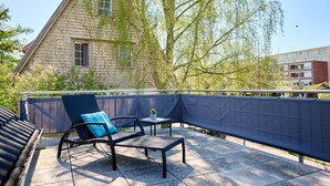 A patio with a chair and table, a stone building with ivy, and a fence.