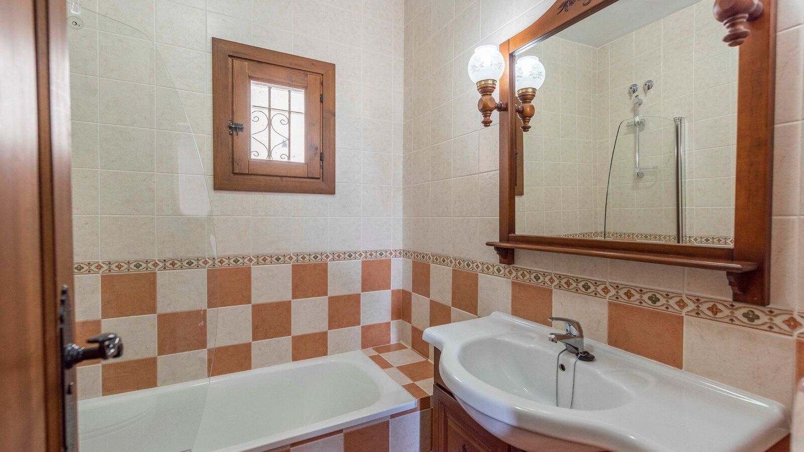 A bathroom with two sinks, a bathtub, a window, and a mirror.