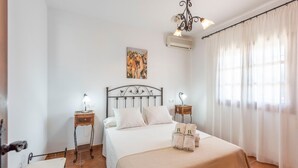 A neatly arranged bedroom with a bed, two bedside tables with lamps, a ceiling light fixture, and a painting on the wall.