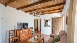 A living room with wooden furniture, a television, and a chandelier.