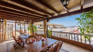 A wooden deck with a table and chairs, overlooking a cityscape. - Castillo de la Hazalara Cómpeta by Ruralidays (Málaga)