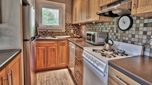 Una cocina moderna con armarios de madera, un refrigerador de acero inoxidable, un microondas, una estufa y una ventana.