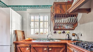 Een keuken met een houten kookeiland, een inbouwfornuis, een spoelbak en een raam met uitzicht op groen.