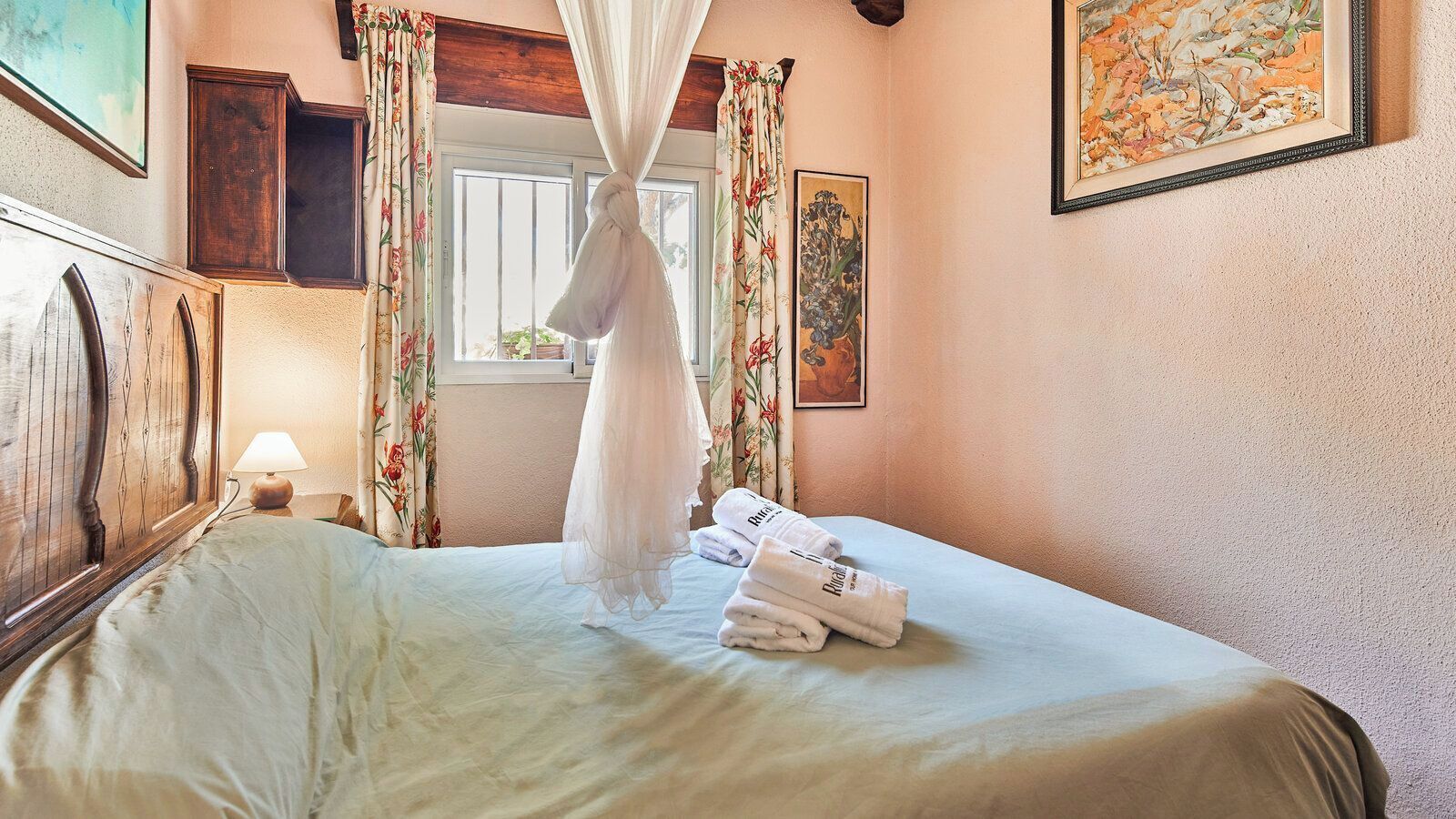 Una habitación de hotel con cama, dosel y ventana con cortinas.
