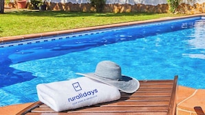 Een zwembadgedeelte met een handdoek en een hoed op een houten stoel, en een bord met de tekst 'ruralidays'.