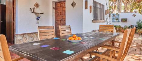 A wooden dining table with chairs, a plate of oranges, and decorative tiles on the floor.